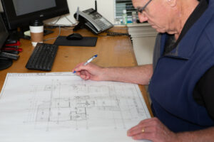 Brian Gannon – Founder + Project Manager, Gannon Construction Company at his desk with plans
