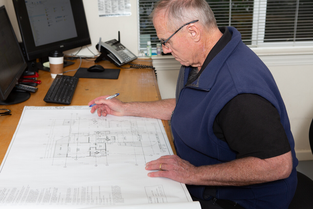 Brian Gannon – Founder + Project Manager at his desk with plans ...